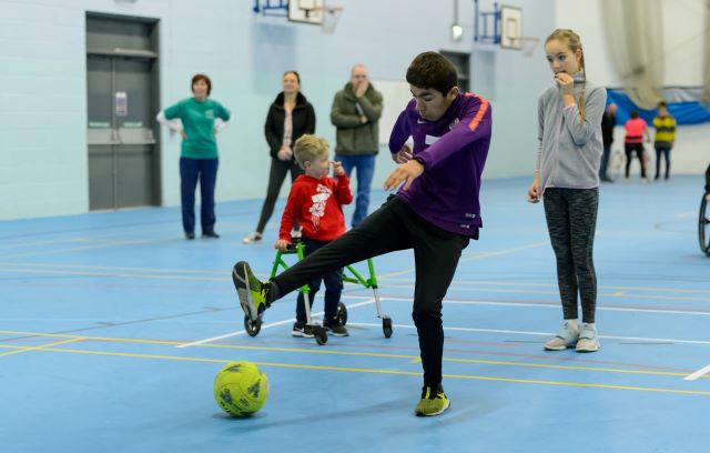 boy kicking football in sports hall