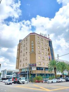 新山Koho Hotel - Johor Bahru的一座大型建筑,前面有汽车停放