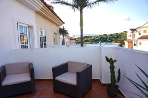 塔里法Tarifa Family House 5 min walk to the beach and old town的棕榈树阳台的两把椅子