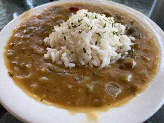 A bowl of thick-looking creole stew with a dollop of rice in the middle.