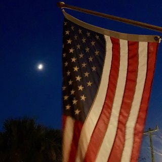 A US flag hanging in front of a night sky.