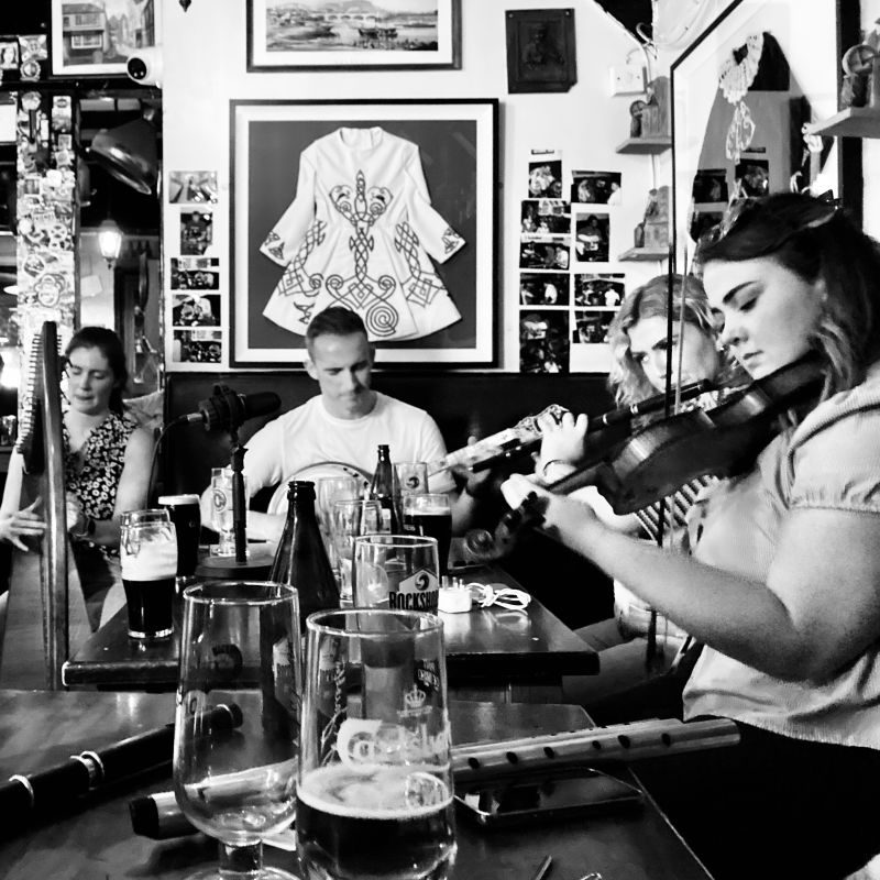 A man on banjo and three women on harp, flute, and fiddle.