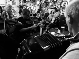 Looking over the shoulder of an accordion player at a rake of fiddlers.