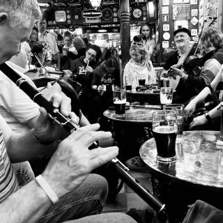 A flute player in the foreground and loads of musicians all in a row in an ornate pub.