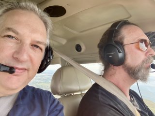 A selfie of me in a cockpit with a headset on sitting next to Andy Budd who is flying, complete with aviator sunglasses.