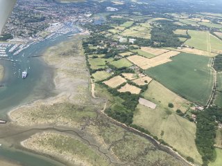 Looking down on a green and brown coastal landscape where a river enters the sea.