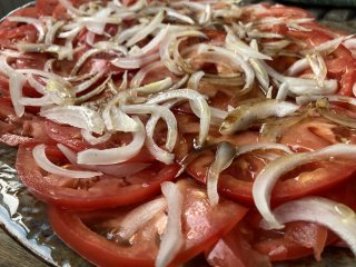 A platter of sliced tomatoes with thinly sliced bits of onion.