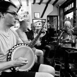 A young man playing banjo in the pub.