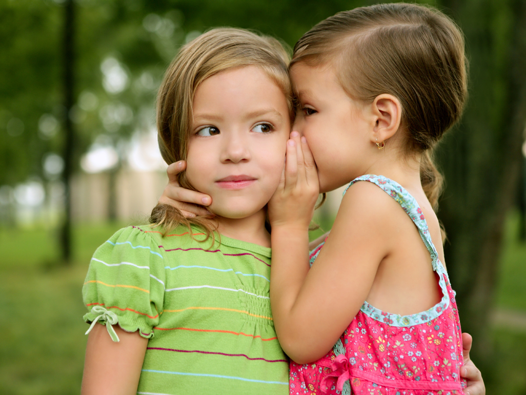 two little girls telling secrets to each other