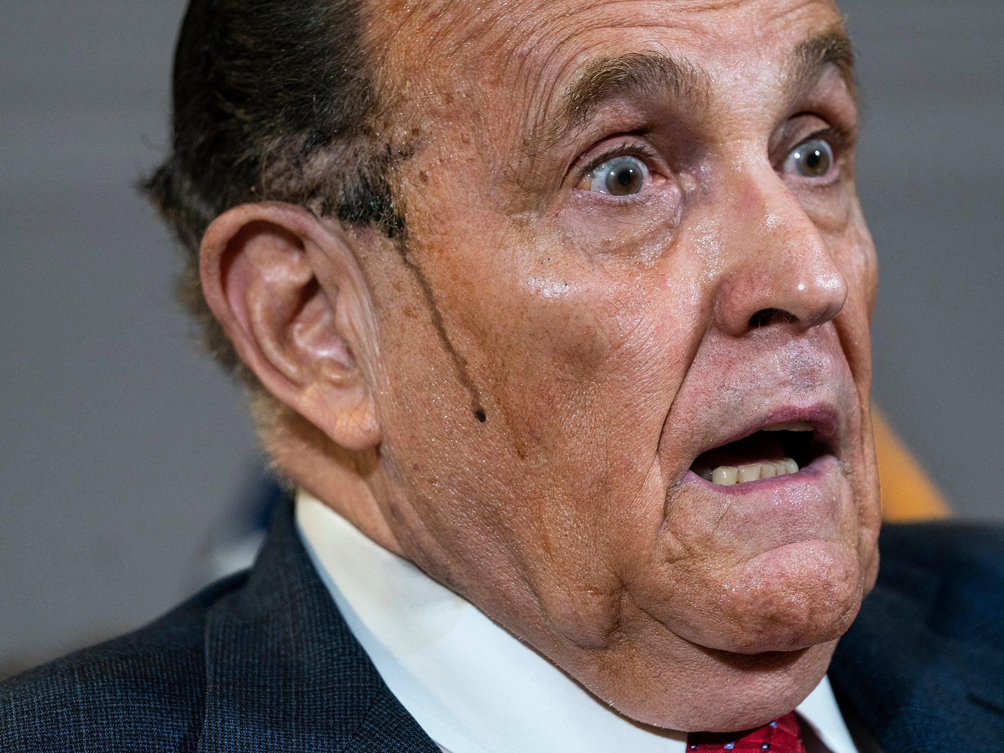 <p>Hair dye runs down Giuliani’s cheek during a bizarre appearance at a press conference</p>Getty