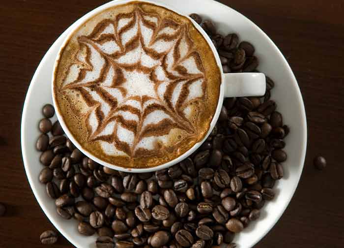 Pinwheel mocha design on white plate with coffee beans from gourmet grind