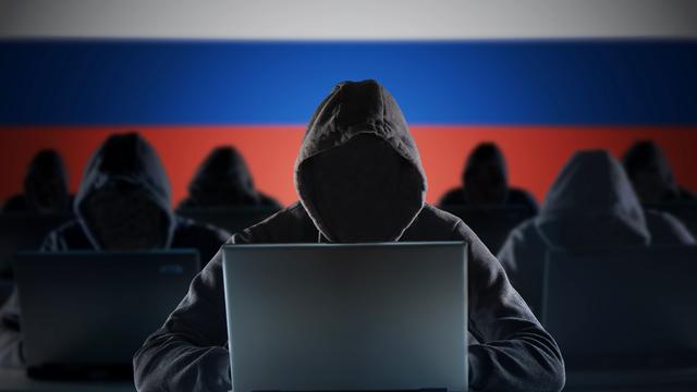 Anonyme russische Hacker vor einem Laptop. Russland Flagge im Hintergrund.