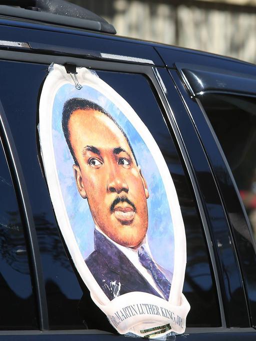 Ein großer Aufkleber mit dem Gesicht von Martin Luther King klebt auf einem Autofenster. Der Beifahrer streckt den Arm aus dem Fenster.