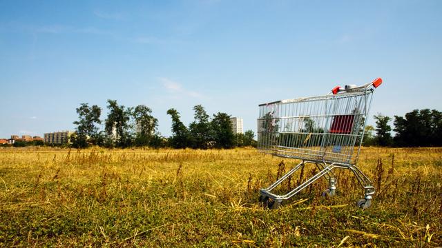 Verlassener Einkaufswagen aus einem Supermarkt inmitten eines Feldes