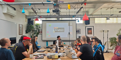 Group of people around a table and projector screen with IWC Brighton displayed