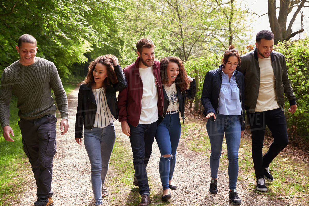 Six young adult friends walking together in a country lane - Stock ...