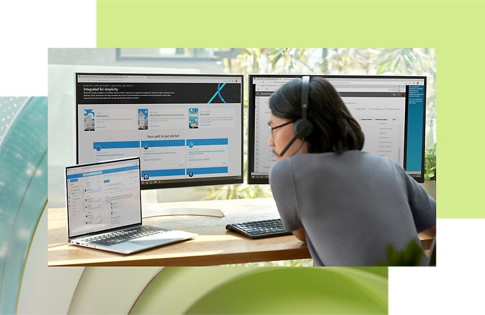 Woman with headphones working on multiple computer screens and a laptop in a modern office setting.