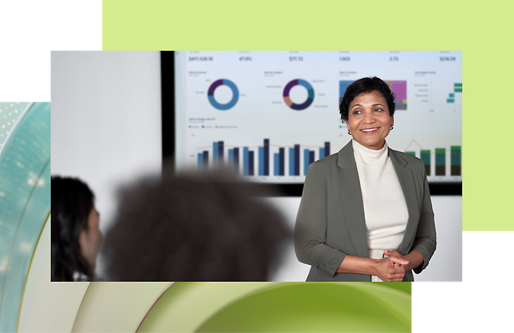 A woman presenting stands confidently in front of a screen displaying graphs, 