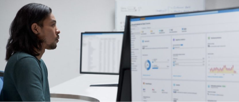 A man sitting in front of two monitors looking at data.