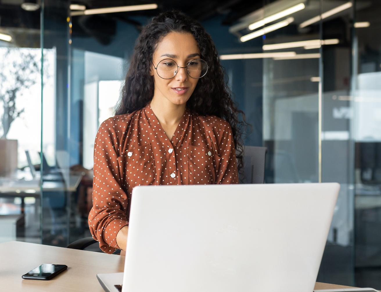 Une jeune fille est assise à un bureau et travaille sur un ordinateur portable.