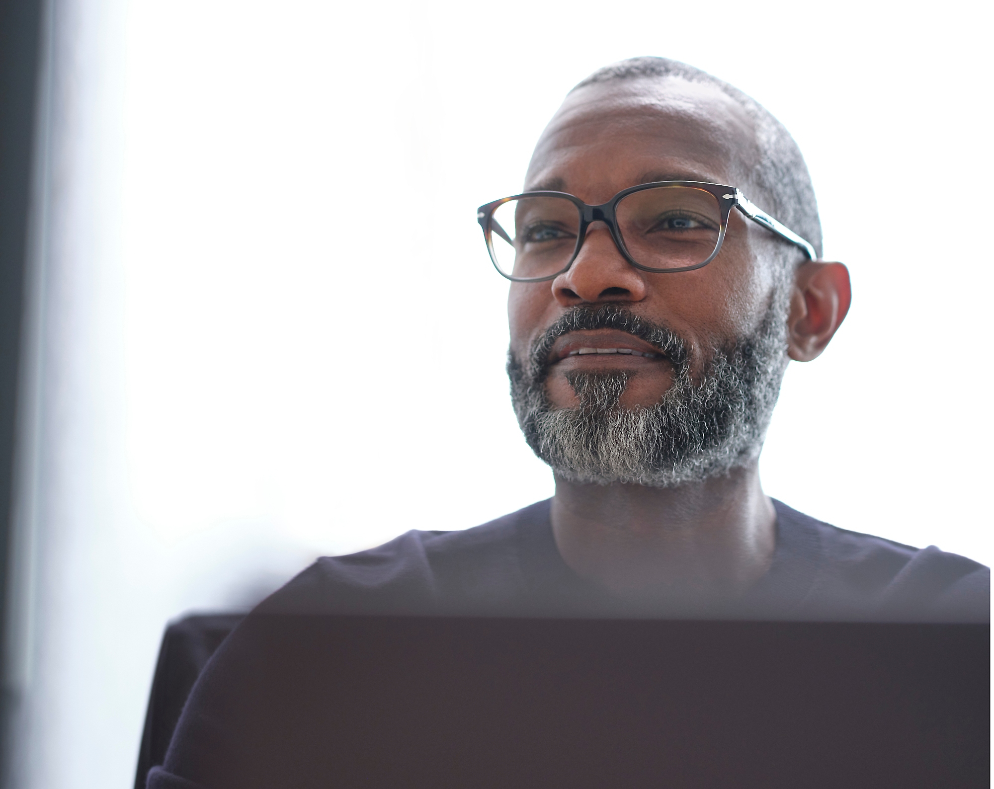 Un homme avec des lunettes et une boucle regardant sur son ordinateur portable