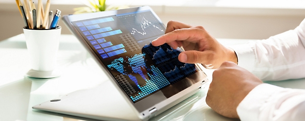 Person analyzing financial data on a tablet screen with interactive charts and graphs, in a bright office setting.