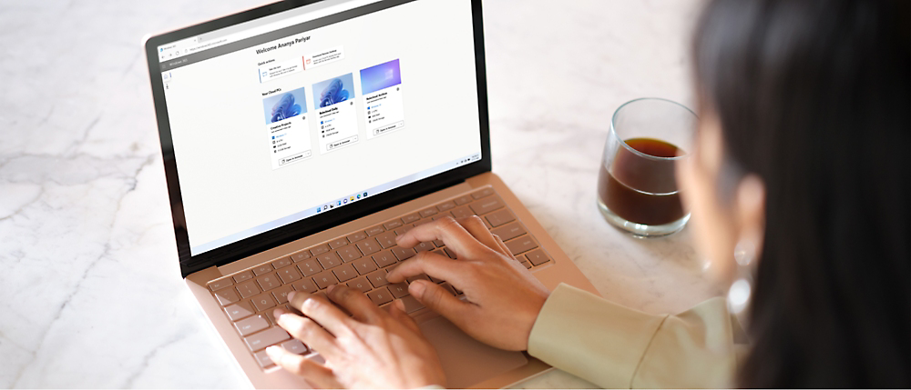 A girl is typing on a computer while having a cup of black coffee.