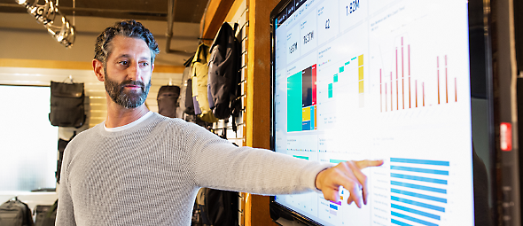 A man pointing finger at a chart displaying on PowerPoint presentation.