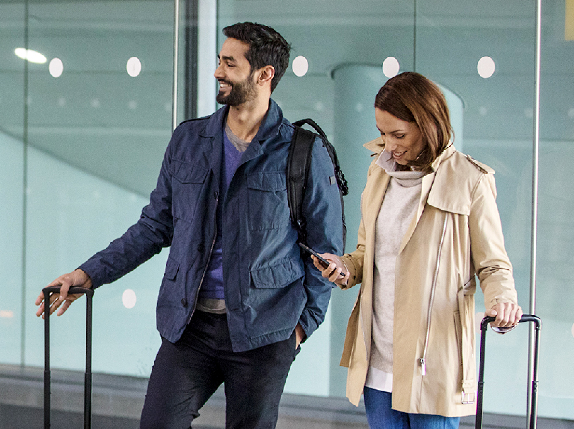 A man and woman with luggage in an airport.