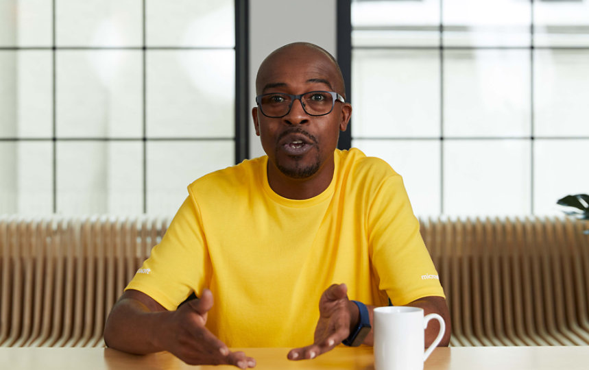 A person speaking while sitting at a table.