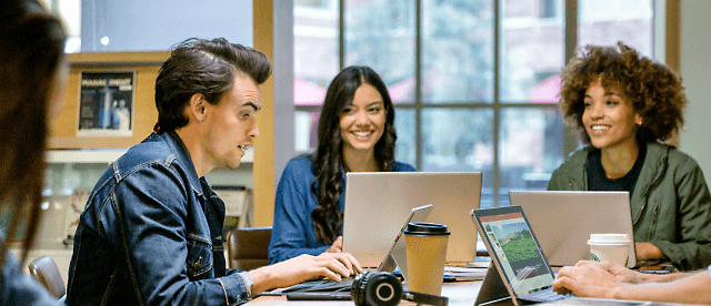 A group of people discussing something in a office room with smiling face