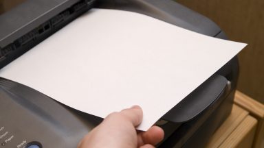 Someone touching a piece of paper that's sitting in a printer