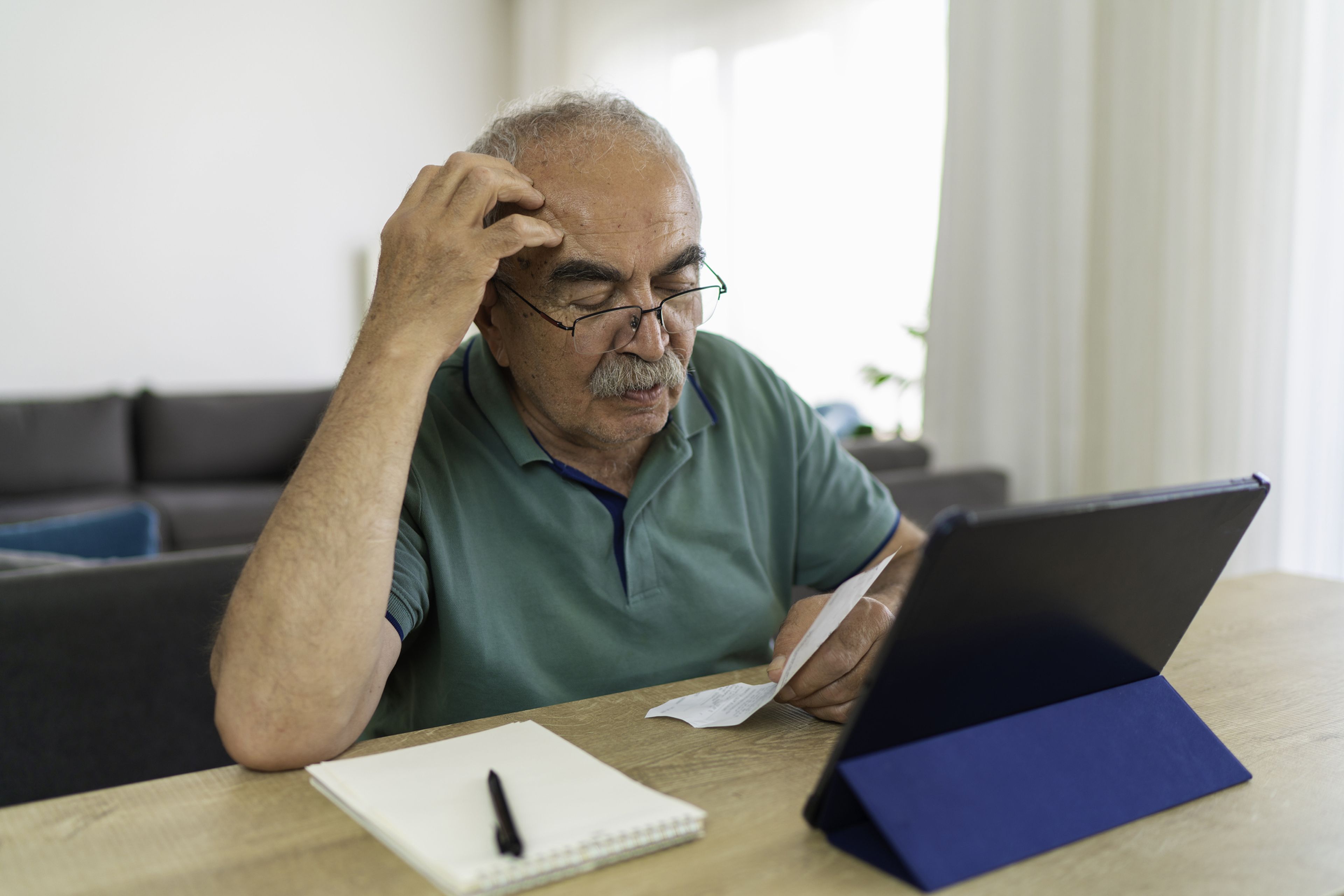 Un hombre con una tablet y varios papeles.