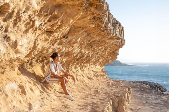 Serenity at Sunset: Man Contemplating by Ocean Rock