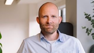 A head and shoulders photo of Qodea's CEO, Tom Ray. He is facing directly towards the camera wearing a light blue shirt.