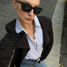 Christie Tyler in black sunglasses, a blazer, and a button down shirt.