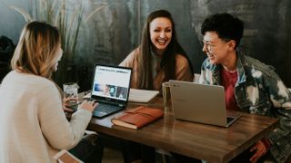 A group of young professionals sitting together with their laptops on the table