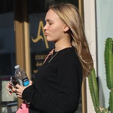 Lily Rose Depp in a black sweater, jeans, white socks, and ballet flats.