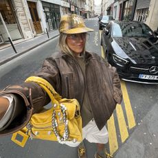 Sofia Coelho in a leather bomber jacket, yellow hat, and yellow Balenciaga purse.