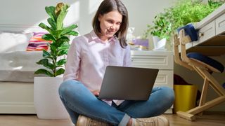 A woman sitting cross-legged on the floor and using a laptop