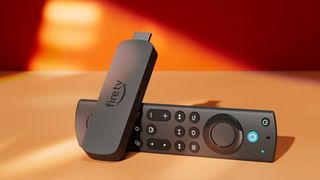 Amazon Fire TV Stick 4K on a table with an orange wall in the background