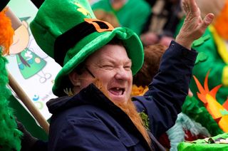 An unidentified man in a St. Patrick's Day parade waving at the crowd wearing a green leprechaun hat and laughing March 17, 2012, Cork, Ireland. 