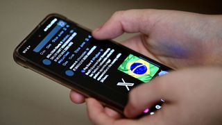 A Brazilian user of the social network X, formerly Twitter, browses posts on a cell phone in Brasilia on August 31, 2024.