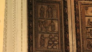 A wooden door at the Santa Sabina Church in Rome shows Jesus with a “wand&quot; performing miracles: (top to bottom) Jesus raising Lazarus; Jesus multiplying loaves and fish; Jesus turning water into wine. 