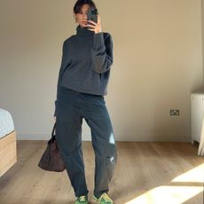 Marianne Smyth in a grey sweater, cargo pants, and green sneakers.