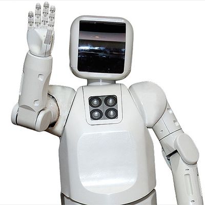 A white robot with a black face plate waves at the camera.