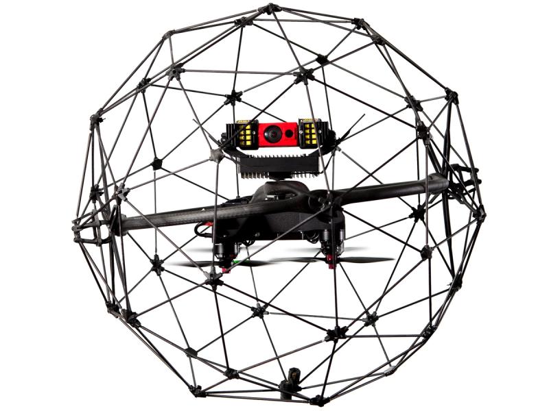 A black drone with electronics sits in the middle of a protective spherical carbon fiber cage.