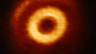 This image from the Atacama Large Millimeter/submillimeter Array shows a central ring of matter and a crescent structure within the circumstellar disk around V1247 Orionis. Image credit: ALMA / ESO / NAOJ / NRAO / S. Kraus, University of Exeter.