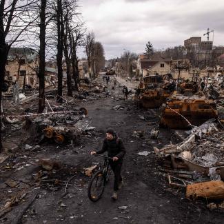 A man pushes his bike through debris and destroyed Russian military vehicles on a street on April 06, 2022 in Bucha, Ukraine. The Ukrainian government has accused Russian forces of committing a "deliberate massacre" as they occupied and eventually retreated from Bucha, 25km northwest of Kyiv. Hundreds of bodies have been found in the days since Ukrainian forces regained control of the town. 