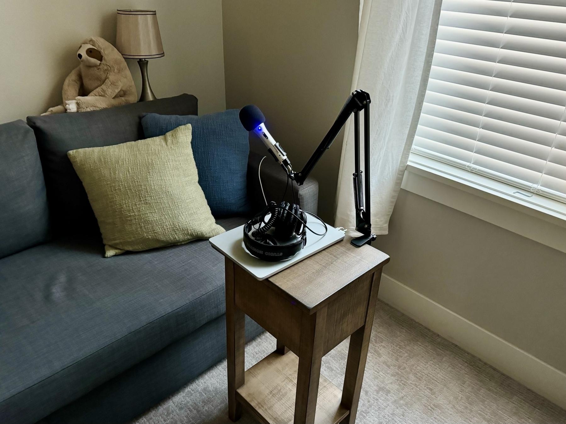 Small end table with microphone and computer in front of a couch. 